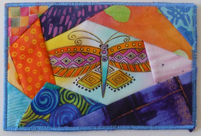 A fabric postcard, crazy quilt with a dragonfly in the center