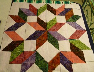 Quilt top blocks for the Carpenter's Star pattern, arranged on top of my bed