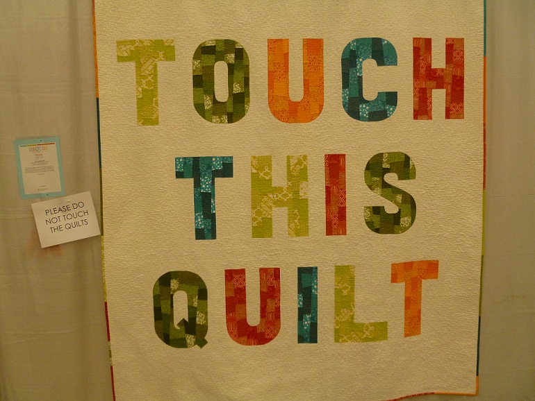 A quilt with the words "touch this quilt" as part of the design