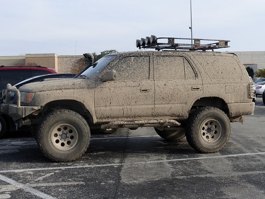 An SUV covered in mud in a parking lot