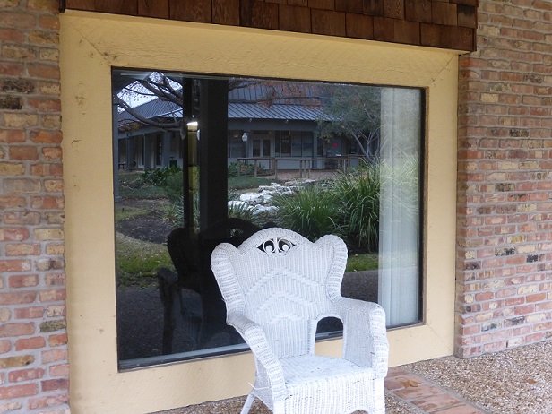 A chair outside a window, with a stream reflected in the window