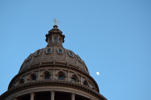 The Texas Capitol building with a half moon in the background