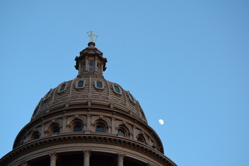 The Texas Capitol building with a half moon in the background