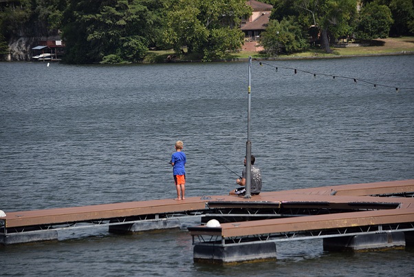 A man and a boy fishing off a pier in the last days of summer
