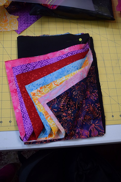 Seven fabrics for a Modern Mola book cover that will be a rooster shape