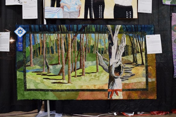An art quilt showing trees that are marked for cutting down, due to the drought