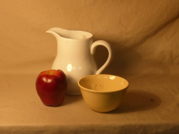 A photo of the still life objects that I chose to paint: a red apple, a yellow bowl and a white ceramic pitcher with handle