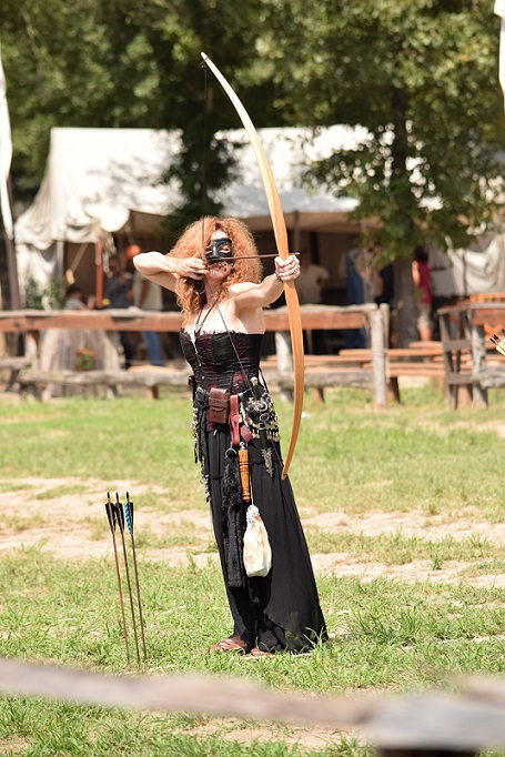 One of the archers, a woman in a black dress and black face mask