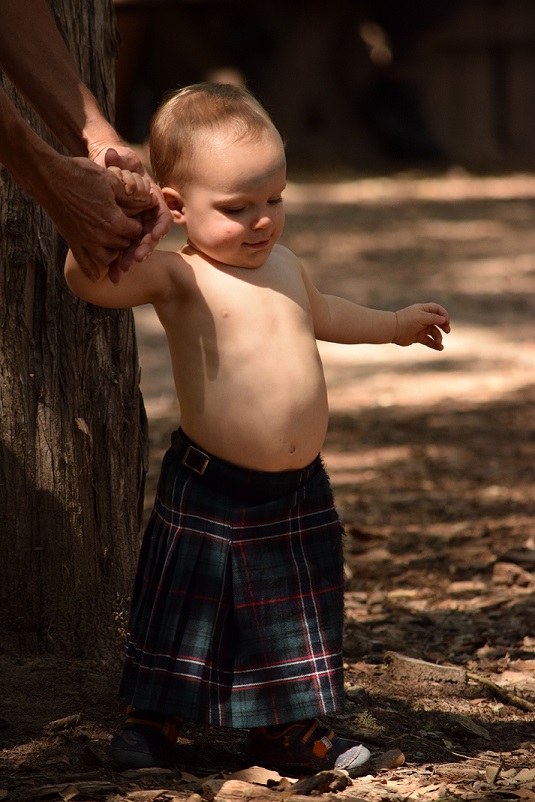 A baby, just learning to walk, in a kilt. So cute.