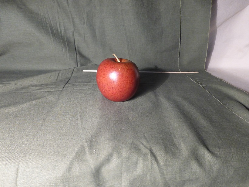 An apple, with a bamboo skewer behind it marking the top of its shadow