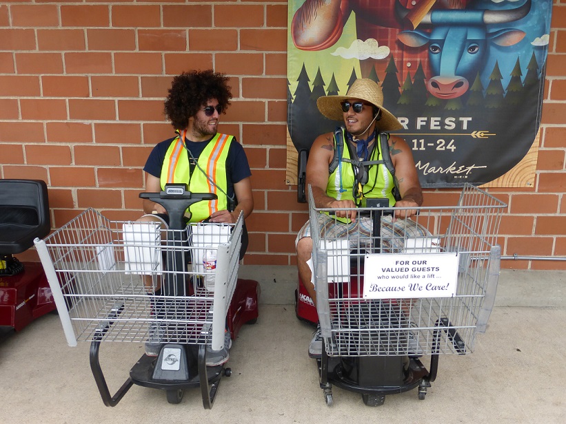 Two grocery store employees sitting on motorized carts chatting with each other