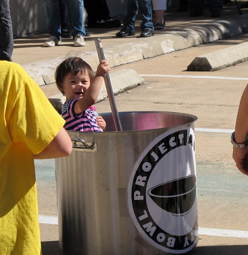 A child in the large soup pot