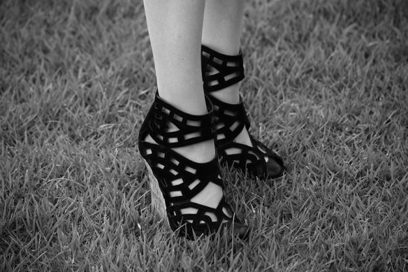 A black and white photograph of a woman's feet in high heels