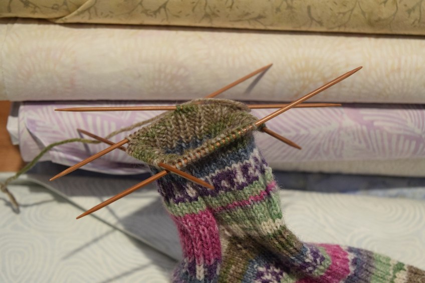 The top of the sock with the four knitting needles