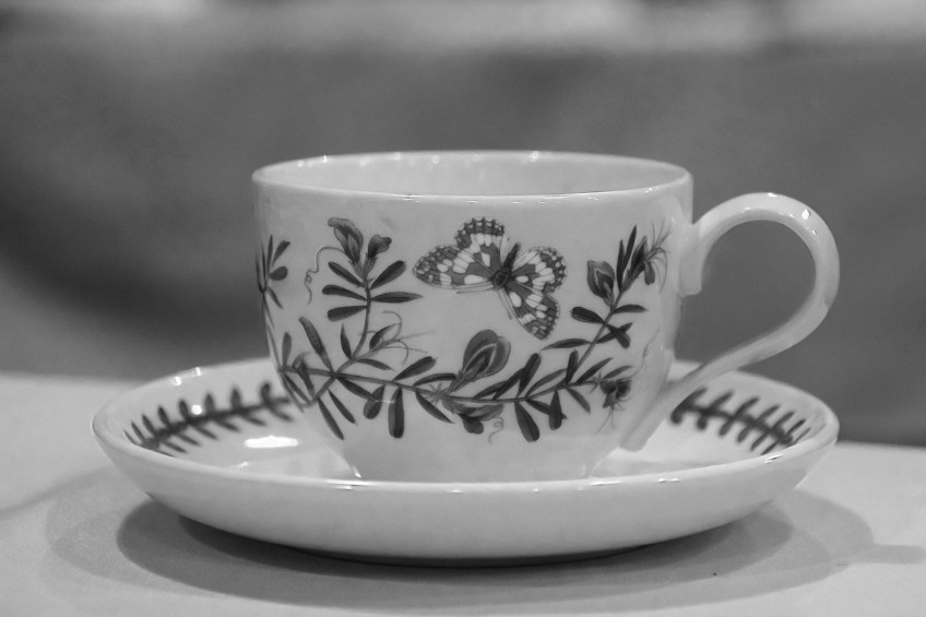 A teacup with butterflies and flowers in black and white