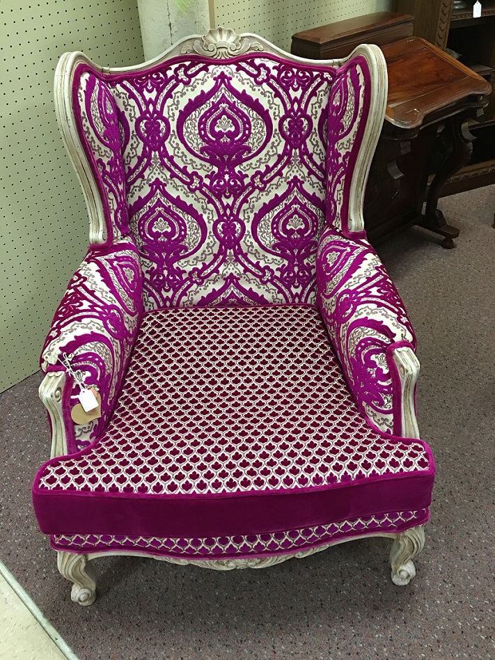 A wing back chair with fabrics all with a fuchsia hue.