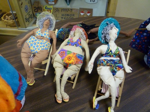 Three dolls of old women in bathing suits sitting in lawn chairs